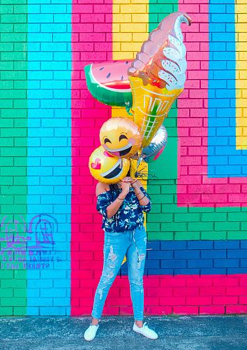 woman covering face with assorted ballons