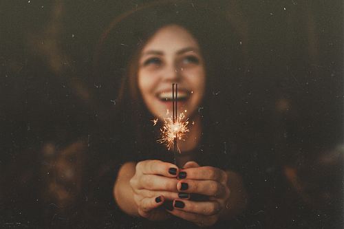 woman holding sparklers while smiling