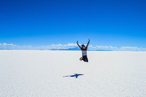 woman jumping under blue skyt