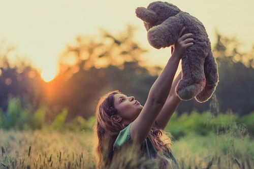 woman lifting brown bear plush toy