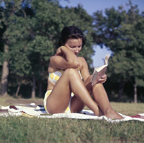 woman sitting on mat reading book