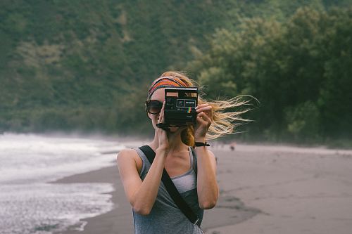 woman standing near seashore taking photo