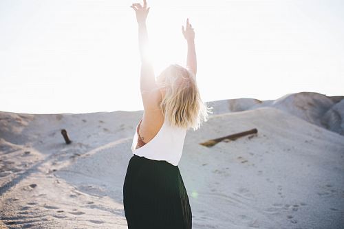 woman standing on the desert while her hands up