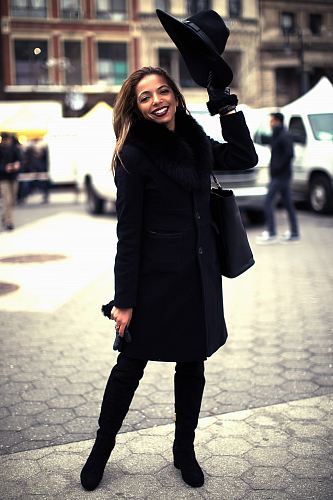 woman wearing black coat standing on gray concrete pavement