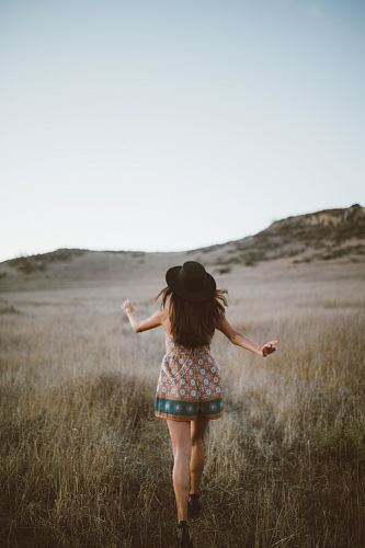 woman wearing brown and green floral romper walking on green grass