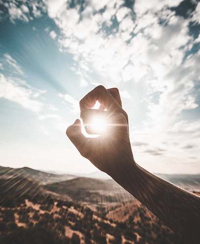sunlight photography of sun glaring through the hole of finger weather