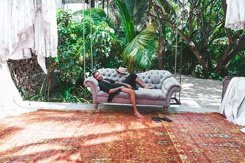 couch person in black robe lying on gray Chesterfield sofa chair