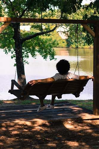 bench person sitting on hammock facing lake swing