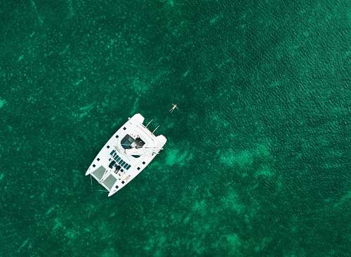 boat aerial view photography of white boat in the middle of body of water during daytime aerial view