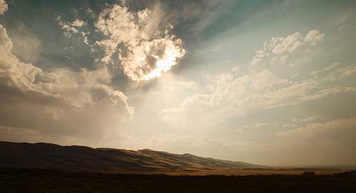 sun mountain during sunrays at daytime clouds