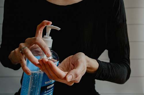 finger person holding white plastic pump bottle coronavirus