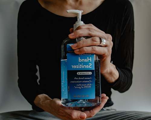 human person holding blue and white pump bottle finger