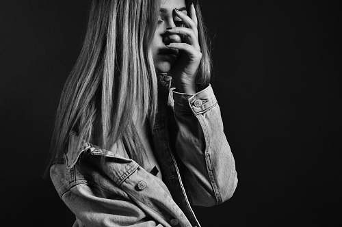 woman woman in denim jacket covering her face with her palm blonde