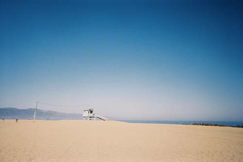 nature white and brown wooden house on brown sand under blue sky during daytime outdoors