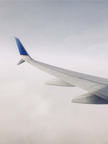 travel white and blue airplane flying over clouds during daytime glider