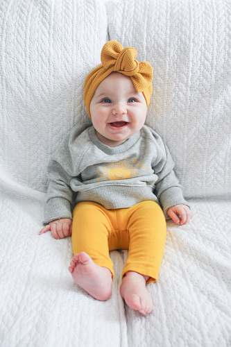 human baby sitting on white sofa person