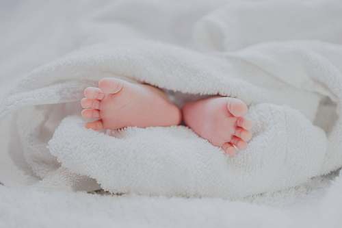 heel barefooted baby covering white blanket toe