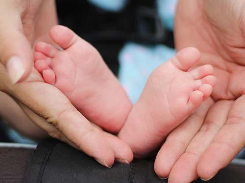 family person holding baby feet hand