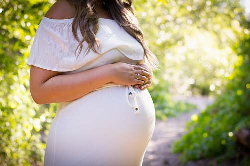 human pregnant woman standing near green plants person