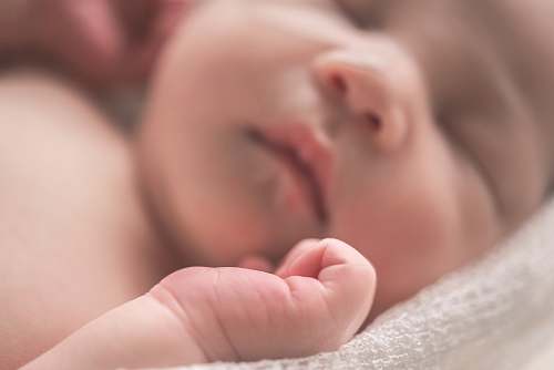 human sleeping baby on white textile newborn