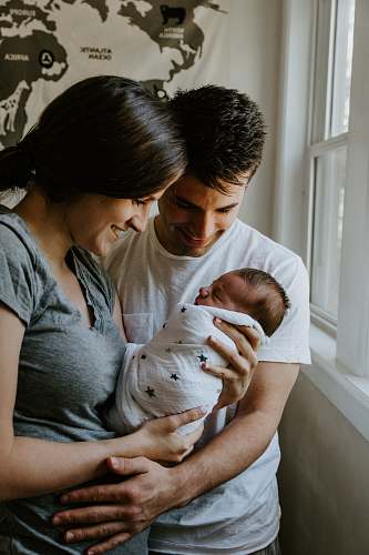 human woman holding baby beside man smiling newborn