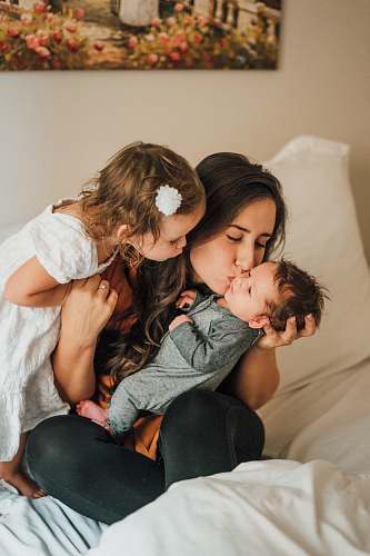 kid woman kissing baby wearing gray onesie family