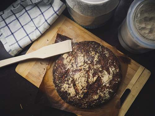 food round baked pastry on brown wooden chopping board with wooden spatula blade