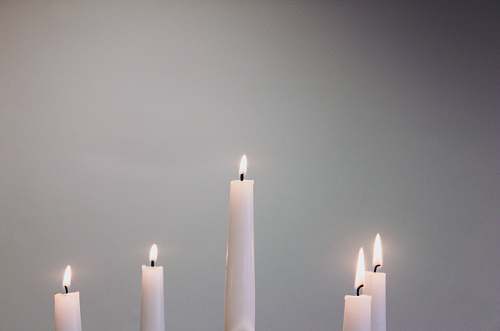 grey five lit white taper candles flame