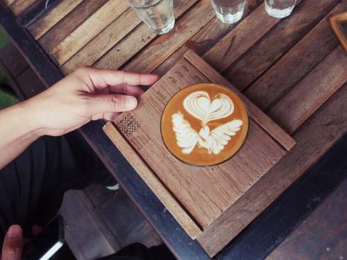 table black ceramic cup on brown wooden coaster hand