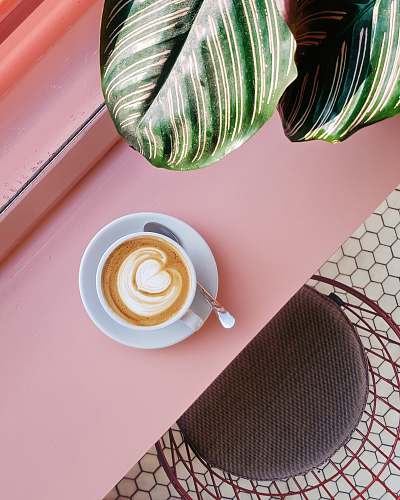 pink cup of coffee on saucer with teaspoon on pink tabletop london