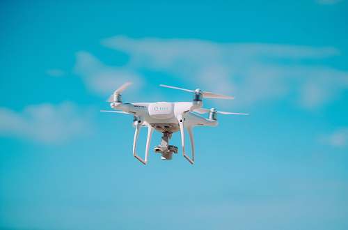 fly white quadcopter flying during daytime flight