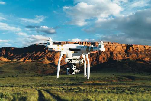 transportation landscape photography of DJI Phantom flying midair in front of mountain biplane