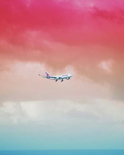 color Qatar Airlines airplane flying under red cloud formation maldives
