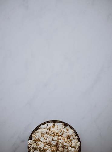 grey bowl of popcorn on white surface seasoning