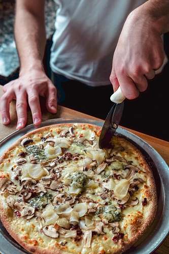 pizza person standing and about to slice pizza human