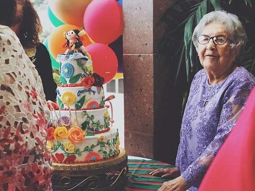 dessert woman wearing purple floral long-sleeved dress besides 4-layer cake cake
