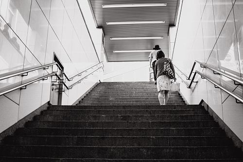 grayscale photography of woman walking on stair