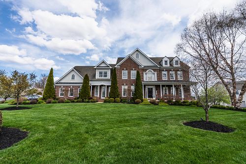 house near bare trees under cloudy sky
