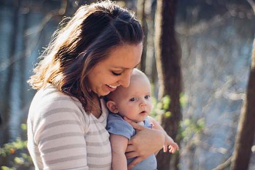 baby woman carrying baby near trees people