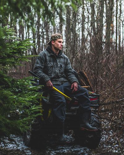 man sitting on yellow all-terrain vehicle in forest