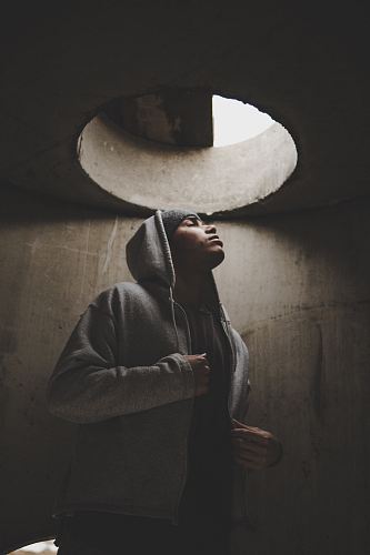 man wearing hoodie standing under manhole