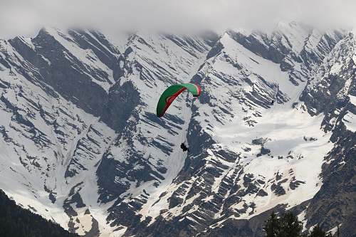 snow person paragliding above snowy mountains during daytime peak