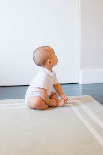 person baby sitting on beige rug human