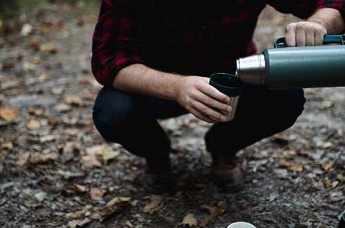 coffee man bending his knees pouring thermal carafe in cup human