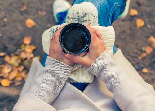human person holding black cup on top of person's lap person
