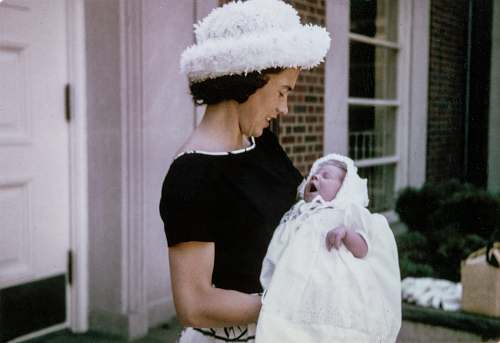 mother woman carrying baby standing near white wooden door baby