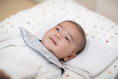 baby baby wearing white shirt lying on bed newborn