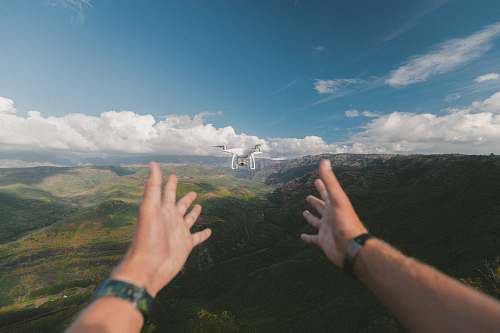 human person pointing both hands on white drone during daytime people