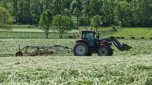 red tractor with farming attachment on field during daytime