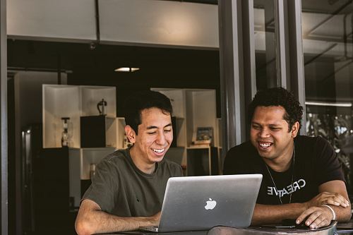 two smiling men looking at MacBook